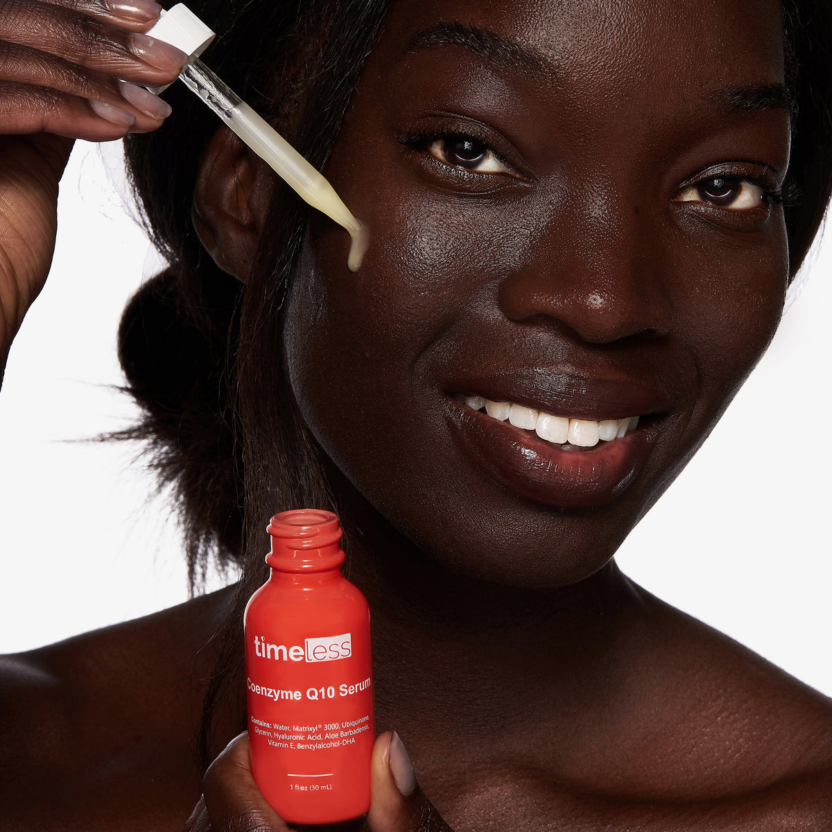 Eine Frau trägt das Timeless Coenzyme Q10 Serum mit einer Pipette auf ihr Gesicht auf. Das gelbliche Serum hat eine leichte, gelartige Konsistenz.