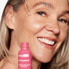 Eine lächelnde Frau trägt das Matrixyl Synthe’6 Serum aus einer rosa Flasche mit einer Pipette auf ihr Gesicht auf.