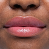 Nahaufnahme der glänzenden, natürlichen Lippen und eines Teils der Nase einer Person mit mittelbrauner Haut.