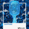 UNbrush Detangling Hair Brush in Sapphire, vor einem Hintergrund aus blauen Edelsteinen.
