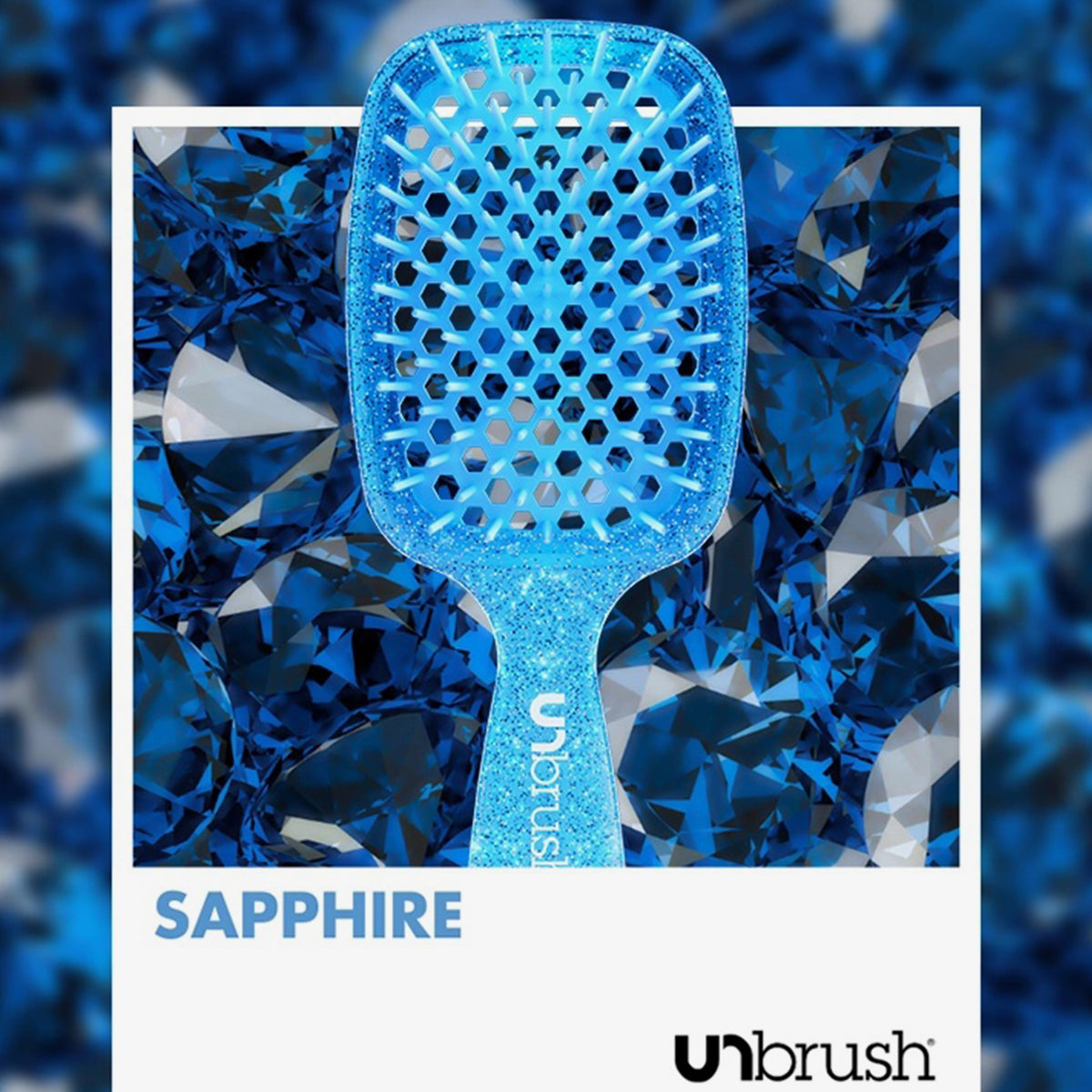 UNbrush Detangling Hair Brush in Sapphire, vor einem Hintergrund aus blauen Edelsteinen.