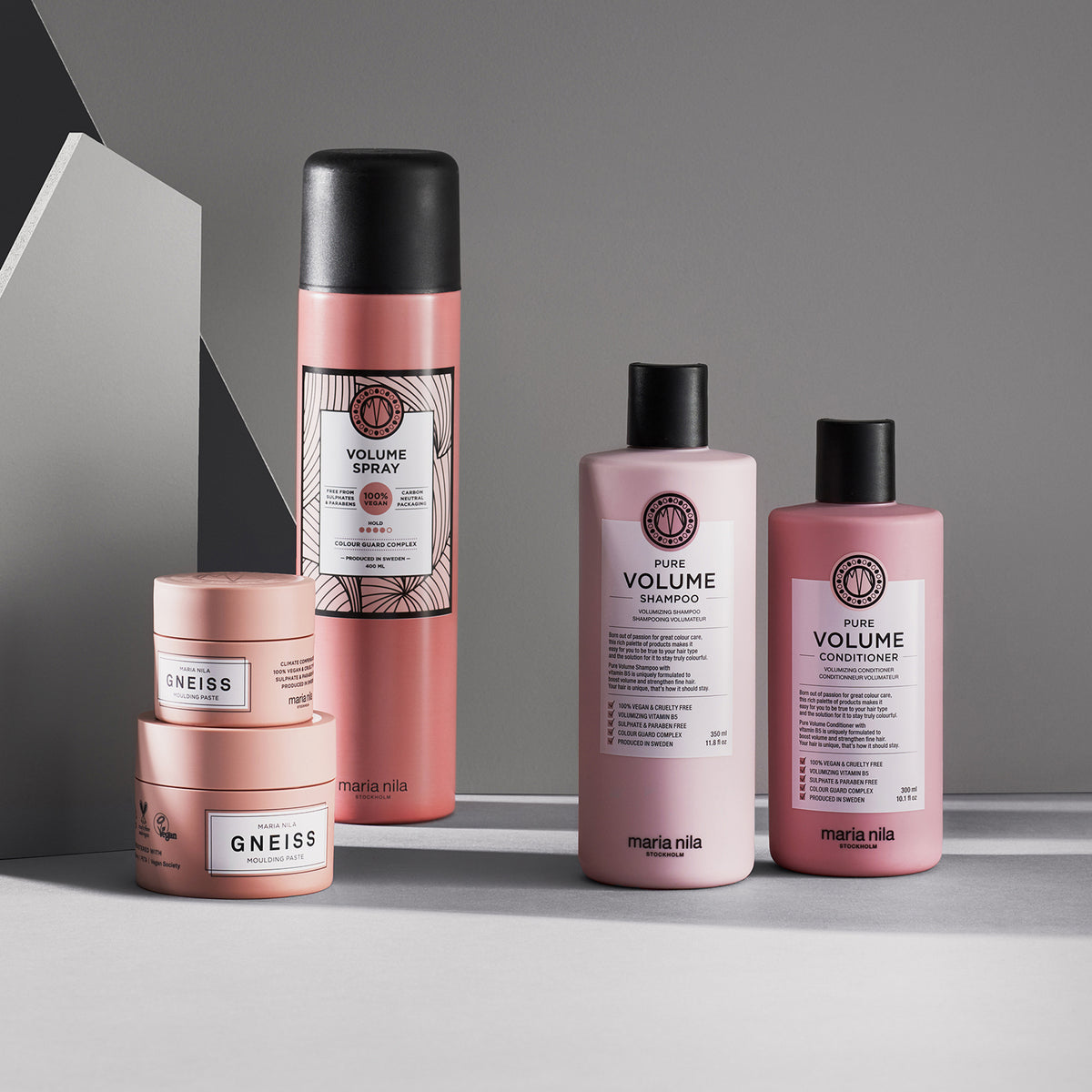 Maria nila Haarpflegeprodukte, wie Volume Spray, Shampoo, Spülung sind auf einer grauen Fläche angeordnet.