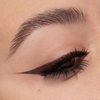 Eine Nahaufnahme eines Auges zeigt einen dramatischen dunkelbraunen Eyeliner und lange, definierte Wimpern.