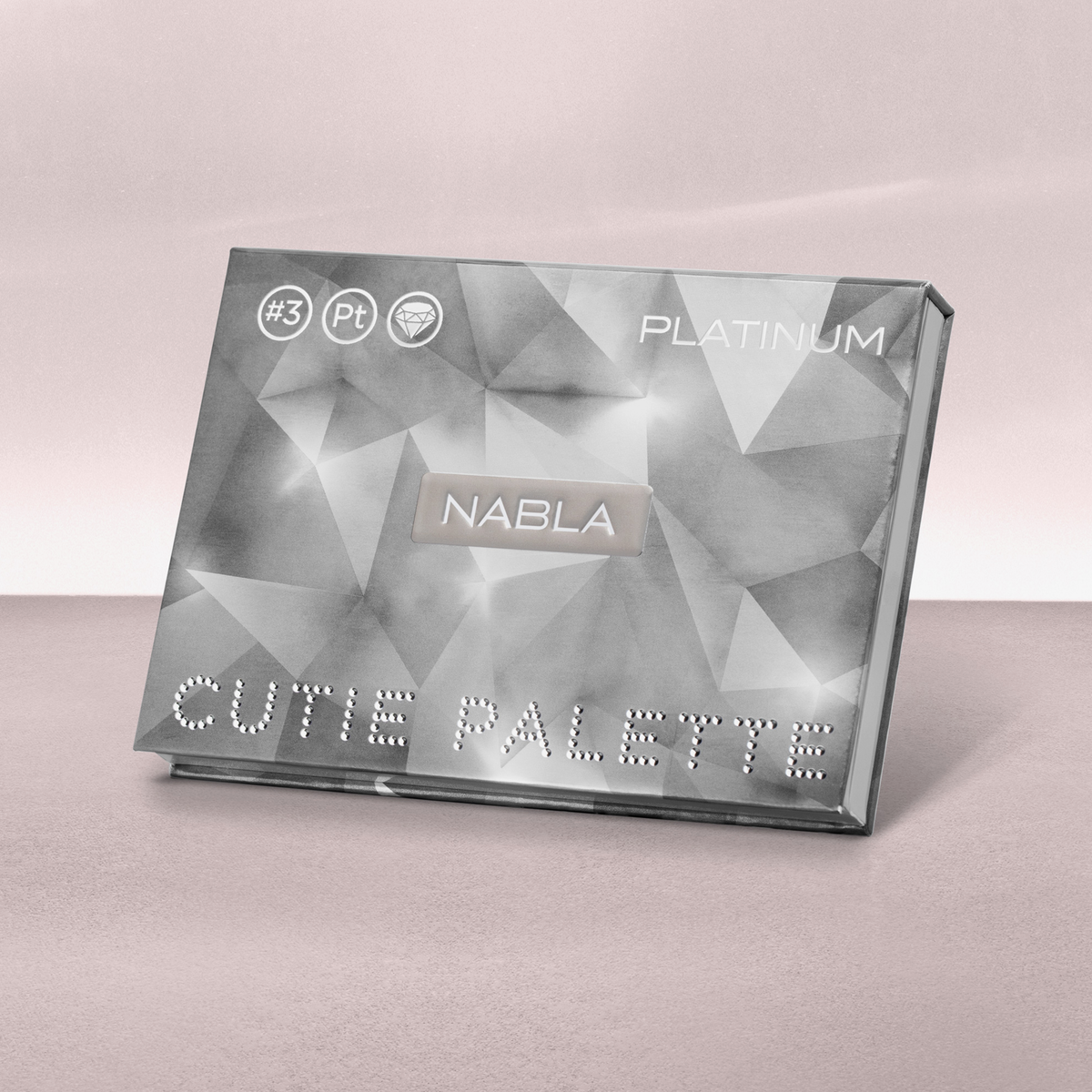 Geschlossene NABLA Cutie Palette „Platinum“ mit grauem, facettiertem Design und silberner Schrift auf rosa Untergrund.