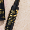 Zwei Flaschen Bondi Sands Aero Self Tanning Foam Liquid Gold auf Sand, von oben im hellen Sonnenlicht fotografiert.