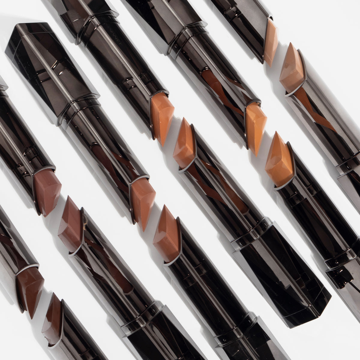 Diagonal angeordnete Reihen von Shapesticks Bronze & Define auf weißer Oberfläche.