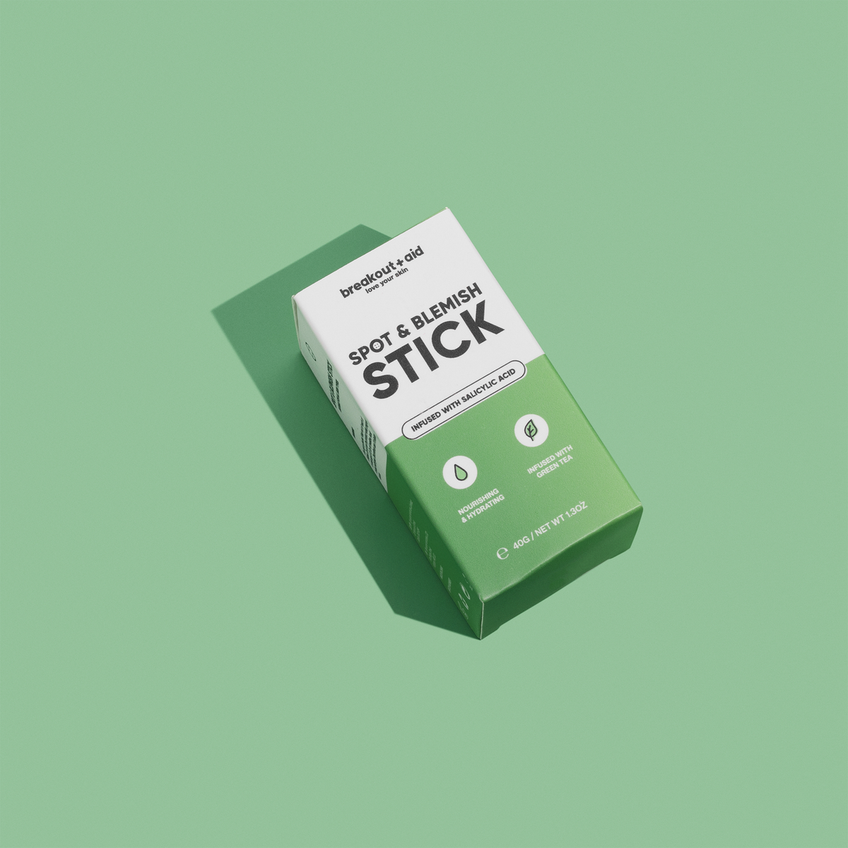 Eine weiß-grüne Verpackung des Breakout+Aid Blemish & Spot Stick, auf der Inhaltsstoffe wie Salicylsäure und grüner Tee angegeben sind.