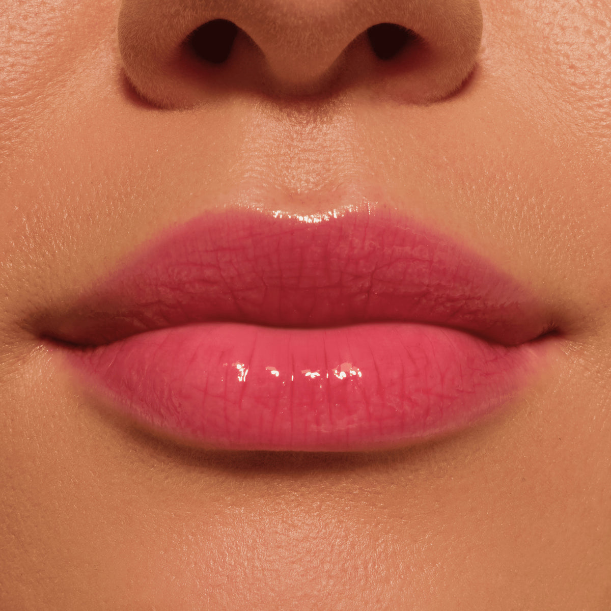 Nahaufnahme von Lippen mit glänzendem, kräftigem Pinkton, aufgetragen mit dem Catrice Colour Cushion Juicy Lip Oil in Crimson Crush.