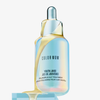 Schillernde Flasche Youth Juice Collagen Scalp Treatment mit gelbem Serum, dass über die Flasche läuft.