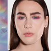 Eine Person mit langen braunen Haaren trägt glänzende Lippen und ein Augen-Make-up in Pastellrosa, Lila und Grün, das mit dem Danessa Myricks Beauty Infinite Chrome Pencil kreiert wurde.
