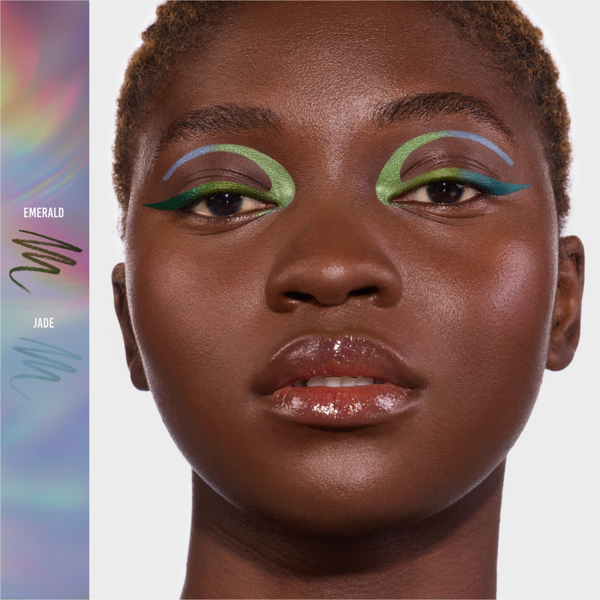 Eine Frau trägt ein grafisches grünes und blaues Augen-Make-up, das mit Danessa Myricks Beauty Infinite Chrome Pencil kreiert wurde, glänzende Lippen und Textfelder mit der Aufschrift Emerald und Jade.