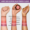 Drei Arme mit unterschiedlichen Hauttönen präsentieren Farbmuster des Yummy Skin Blurring Balm Powder Flushed, in einer Hand ist ein Rouge-Kompaktpuder zu sehen.