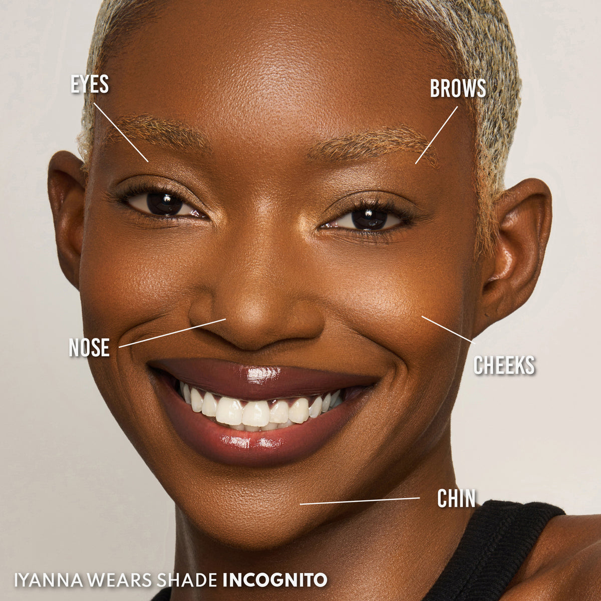 Eine lächelnde Person mit dunklem Hautton trägt den Yummy Skin Blurring Balm Powder Lowlighter Incognito.