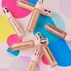 Mehrere Flaschen MAGIC FILTER Glow Booster liegen auf einem bunten geometrischen Hintergrund.