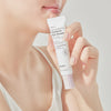 Frau hält vor einem hellen Hintergrund eine Tube Real Complexion Hyaluron Eye Serum vor ihr Gesicht.