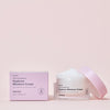 Schachtel und offener Tiegel Hanskin Real Complexion Hyaluron Moisture Cream vor einem hellrosa Hintergrund.