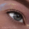 Nahaufnahme eines Auges mit buntem, schillerndem Glitzer-Make-up über dem Augenlid. Text: Ohne Fix Potion aufgetragen.