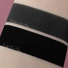 Zwei Farbmuster von Moonshadow Matte Pressed Eyeshadow auf der Haut: eines in Dunkelgrau mit der Aufschrift „Without Fix Potion“, eines in Schwarz mit der Aufschrift „With Fix Potion“.