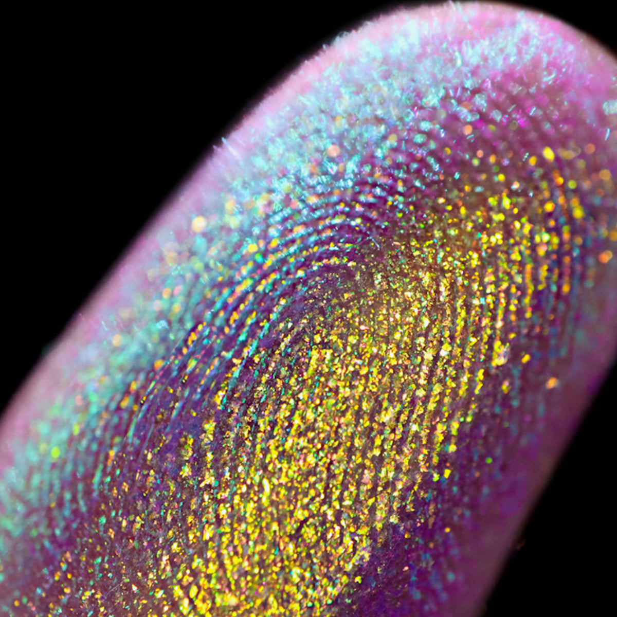 Nahaufnahme einer Fingerspitze, die in den Opal Moonstone Loose Multichrome Eyeshadow Cry Baby getaucht wurde und blau-violett und gelb glitzert.