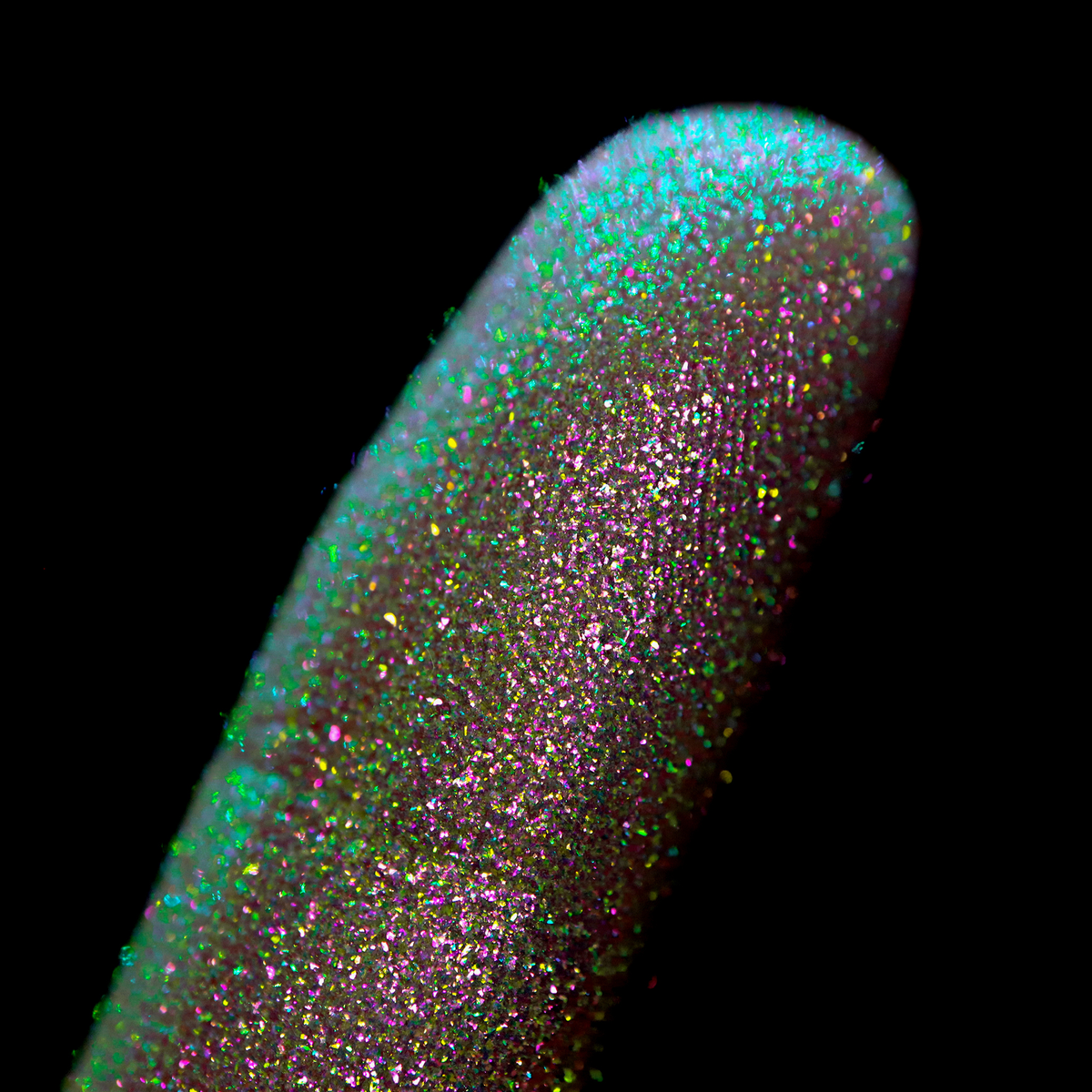 Nahaufnahme einer Fingerspitze, die in den Opal Moonstone Loose Multichrome Eyeshadow Lucky Charm getaucht wurde und grün und rosa glitzert.