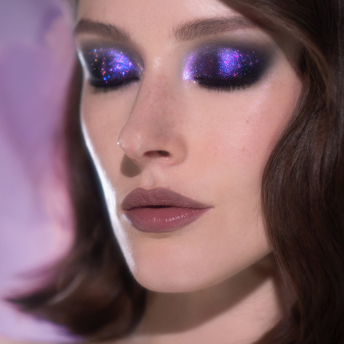 Frau mit geschlossenen Augen trägt lila schimmernden Opal Multichrome Eyeshqdow in der Farbe Night Kiss von Karla Cosmetics.