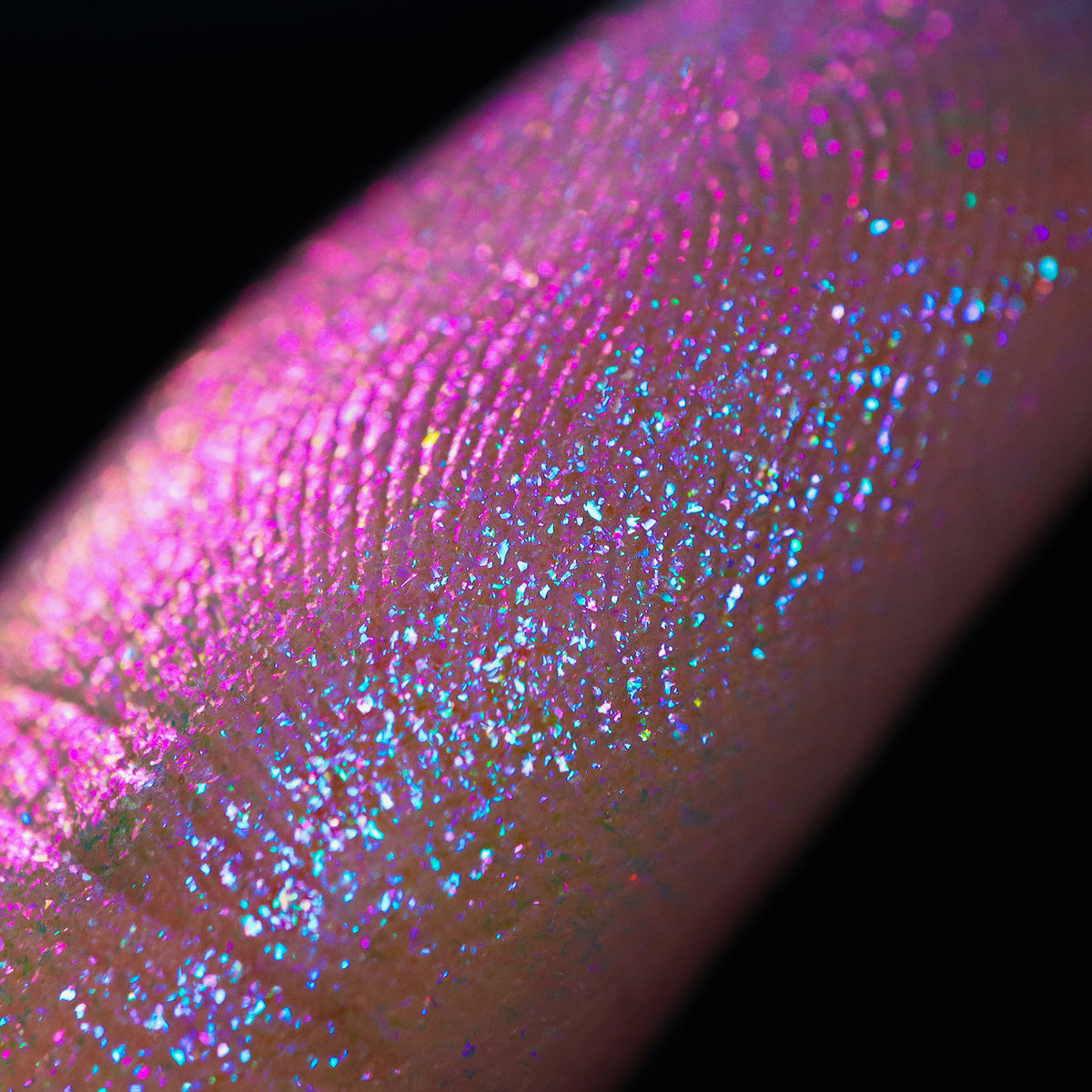 Nahaufnahme einer Fingerspitze, die in den Opal Multichrome Loose Eyeshadow Nightfall getaucht wurde und pink-blau glitzert.