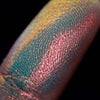 Nahaufnahme einer Fingerspitze, die in den Opal Multichrome Loose Eyeshadow Pillow Fight getaucht wurde und gelb-blau und rosa-bronze glitzert.