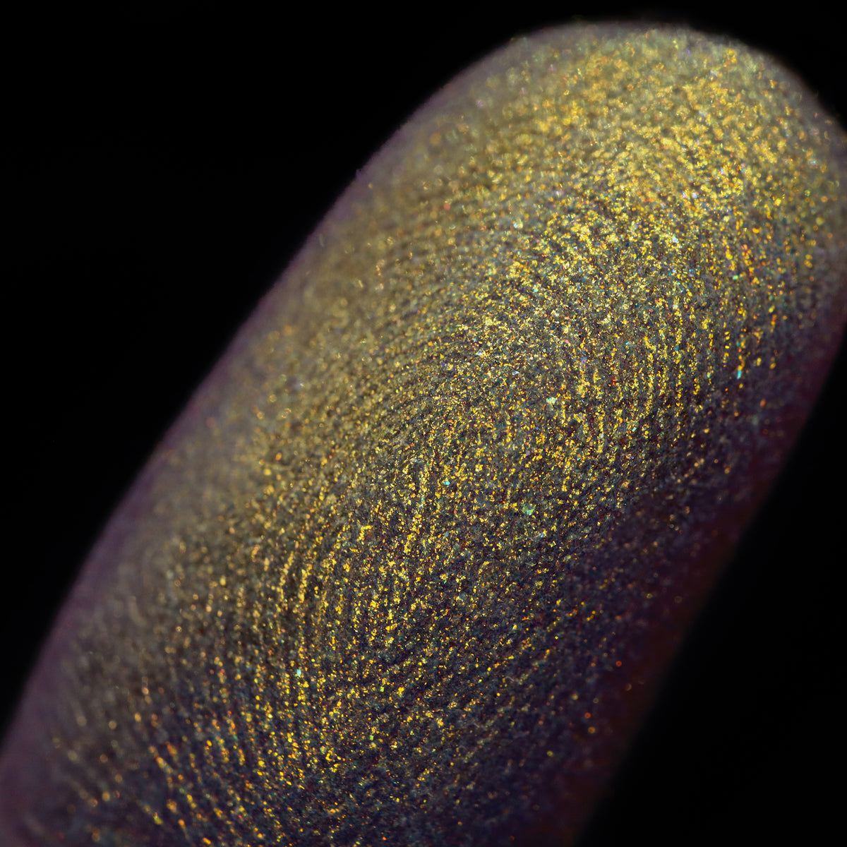 Nahaufnahme einer Fingerspitze, die in den Opal Multichrome Loose Eyeshadow Shooting Star getaucht wurde und gelb-grün-gold glitzert.