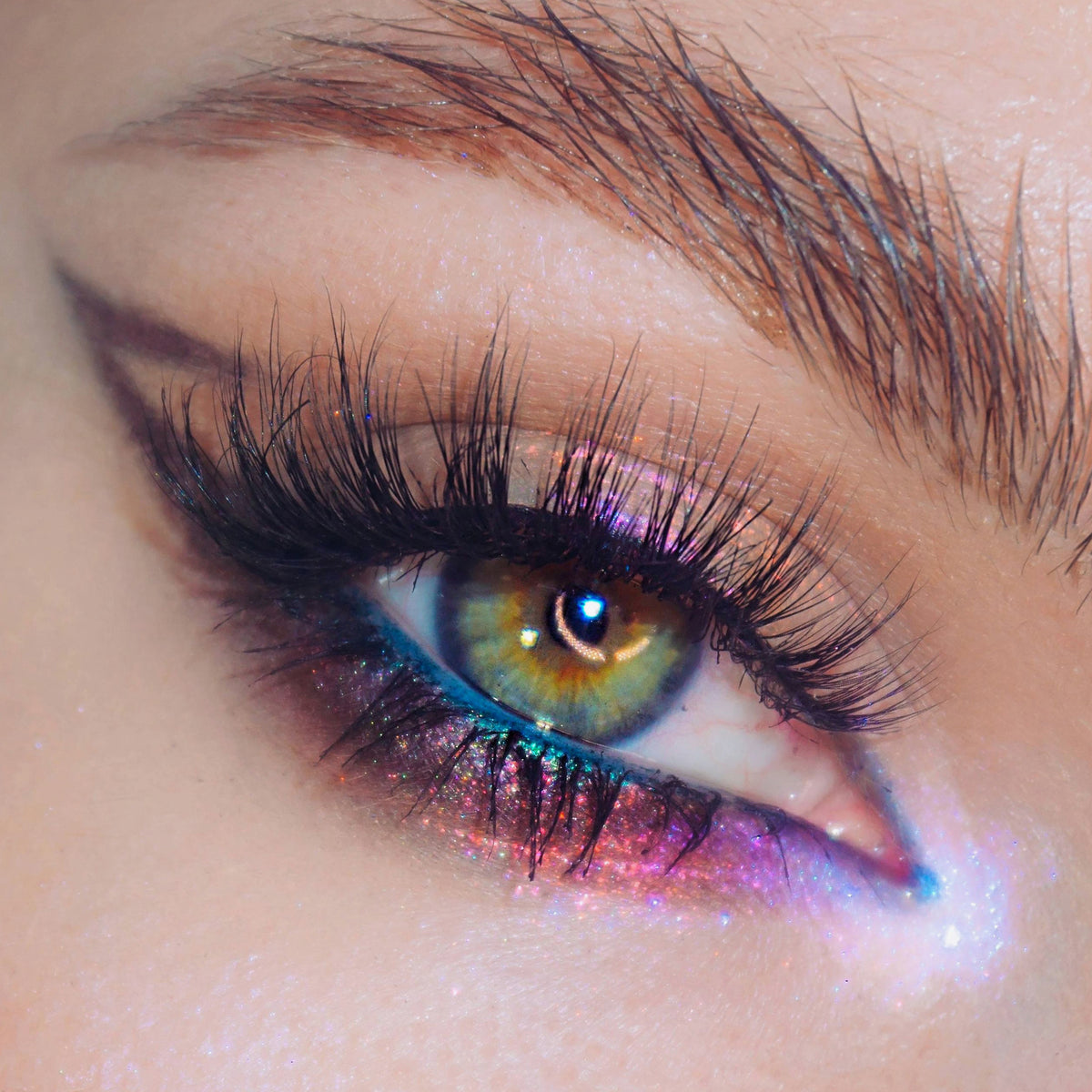 Nahaufnahme eines Auges mit dramatischem Eyeliner und blau-pink-lila schimmerndem Opal Shadow Potion Silky Gel Eyeshadow in Pillow Fight.