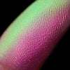 Nahaufnahme einer Fingerspitze, die in den Pastel Duochromes Loose Eyeshadow Cupcake getaucht wurde und hellgrün und pink glitzert.