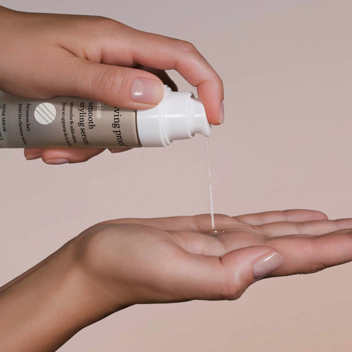 Eine Person gibt vor einem neutralen Hintergrund Living Proof No Frizz Smooth Styling Serum aus der Flasche auf ihre offene Handfläche.