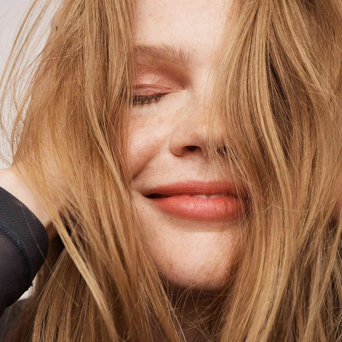 Eine Frau mit langem, rot-blondem Haar zeigt den erfrischten Look des Perfect Hair Day Dry Shampoo von Living Proof.