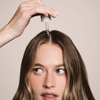Eine Person verwendet das Living Proof Scalp Care Density Serum auf ihrer Kopfhaut.