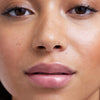 Nahaufnahme des Gesichts einer Person mit glänzenden vollen Lippen, die durch den Lip Glow Oil Balm betont werden