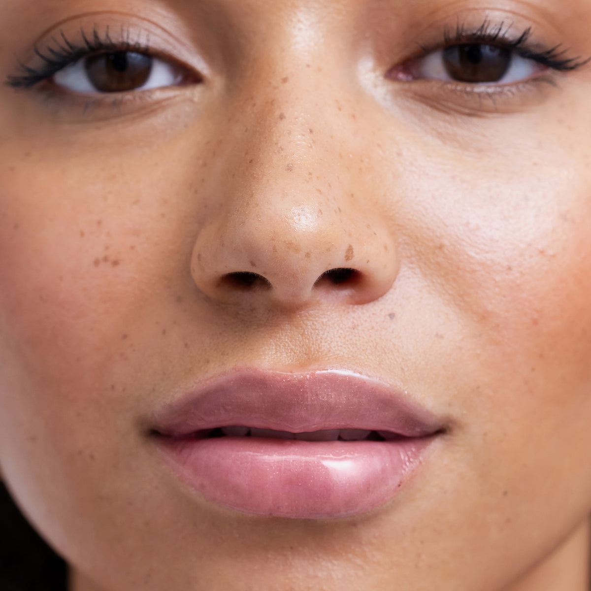 Nahaufnahme des Gesichts einer Person mit glänzenden vollen Lippen, die durch den Lip Glow Oil Balm betont werden
