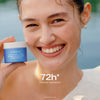 Eine lächelnde Frau hält einen blauen Tiegel Lumene Nordic Hydra [LÄHDE] Intense Hydration Moisturizer in der Hand; der Text lautet "72h* Intense hydration".