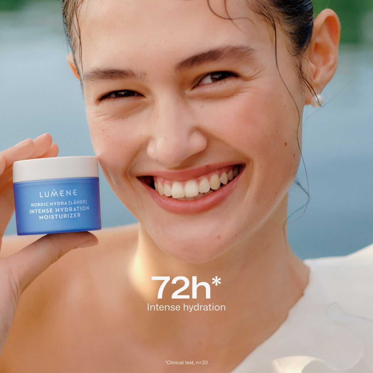 Eine lächelnde Frau hält einen blauen Tiegel Lumene Nordic Hydra [LÄHDE] Intense Hydration Moisturizer in der Hand; der Text lautet "72h* Intense hydration".