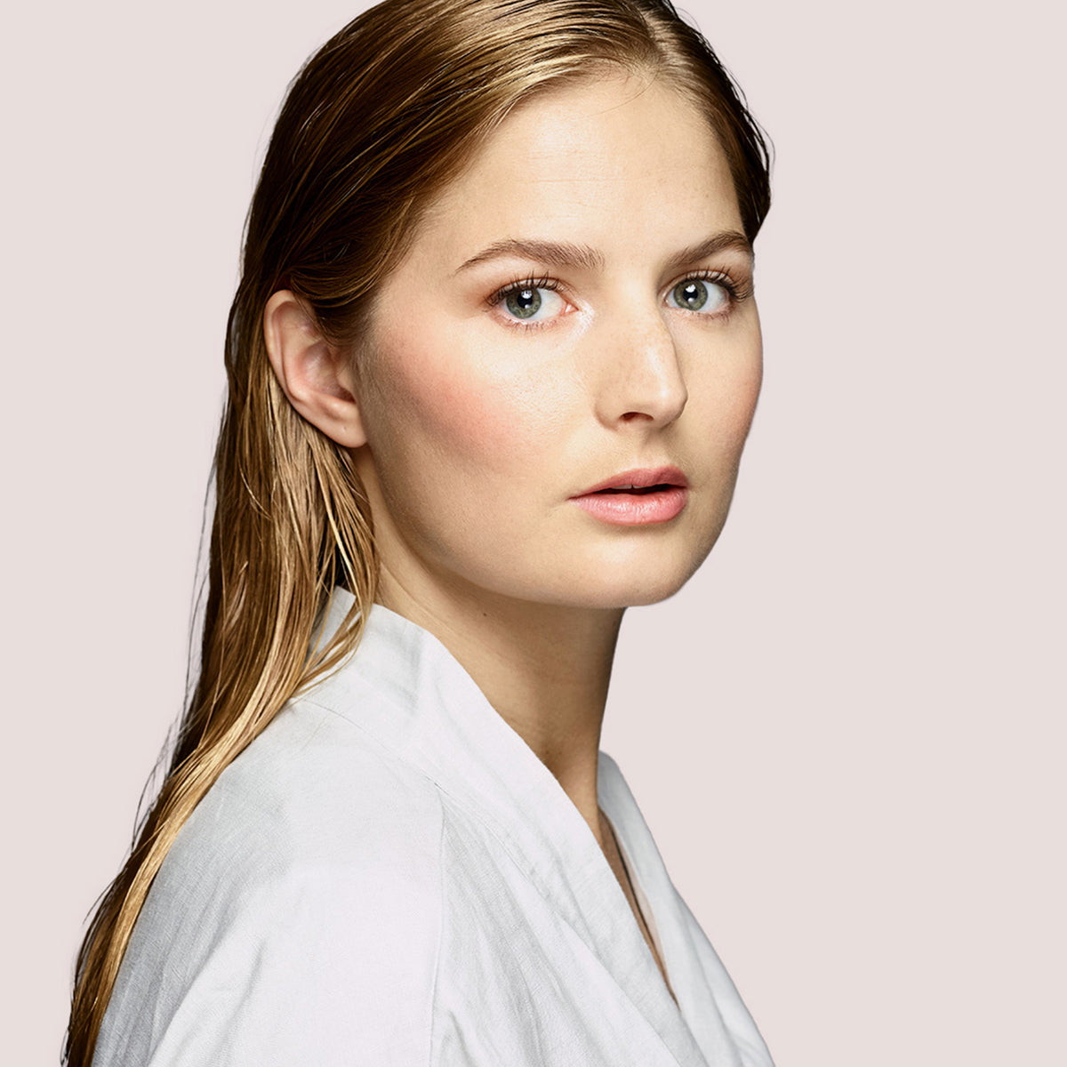 Eine Frau mit nassem, glattem Haar und leichtem Make-up, zeigt Haar nach Anwendung des maria nila Pure Volume Shampoo.