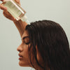 Eine Person trägt das Purifying Cleanse Exfoliating Serum von Maria Nila auf die Kopfhaut auf.