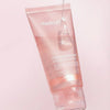 Eine rosafarbene Tube Collagen Night Wrapping Mask mit auf der Kappe aufgetragenem Gel vor einem hellrosa Hintergrund.
