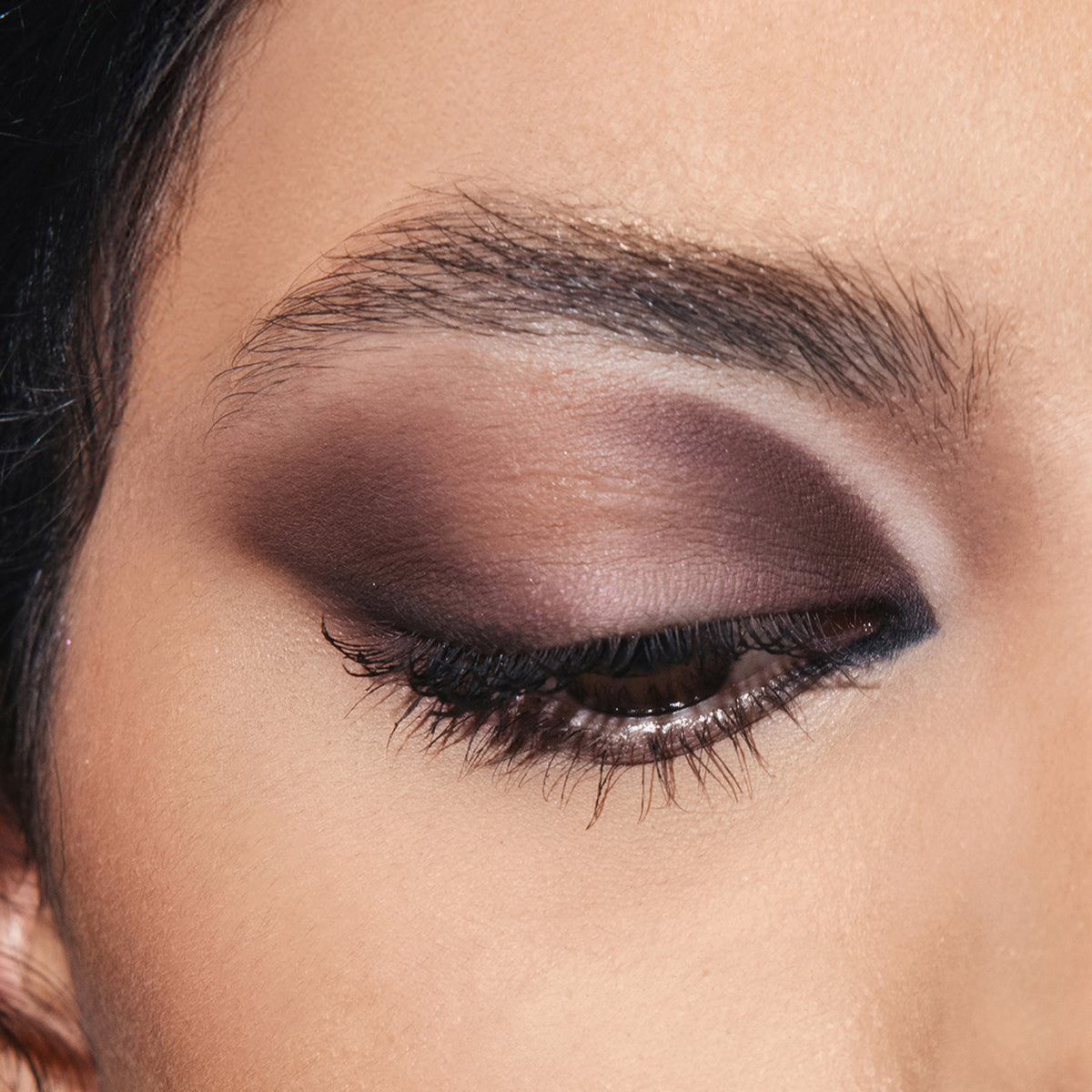 Nahaufnahme eines geschlossenen Auges mit ARCHETYPE Lidschatten von Mesauda Beauty in kräftigen Brauntönen und schwarzem Eyeliner.