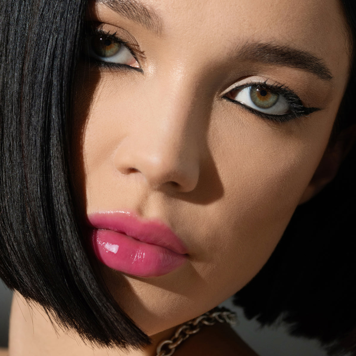 Nahaufnahme einer Frau mit glattem schwarzem Haar, Eyeliner und glänzenden rosa Lippen, geschminkt mit LIP PHENOM™ von Mesauda Beauty.
