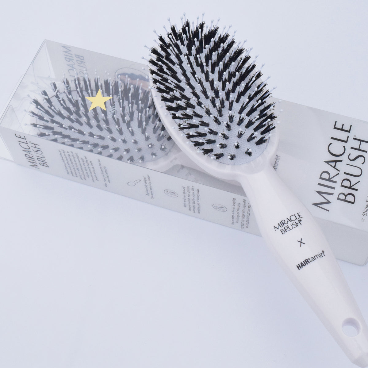 Zwei Stück Miracle Brush® X HAIRtamin® liegen auf weißem Hintergrund.