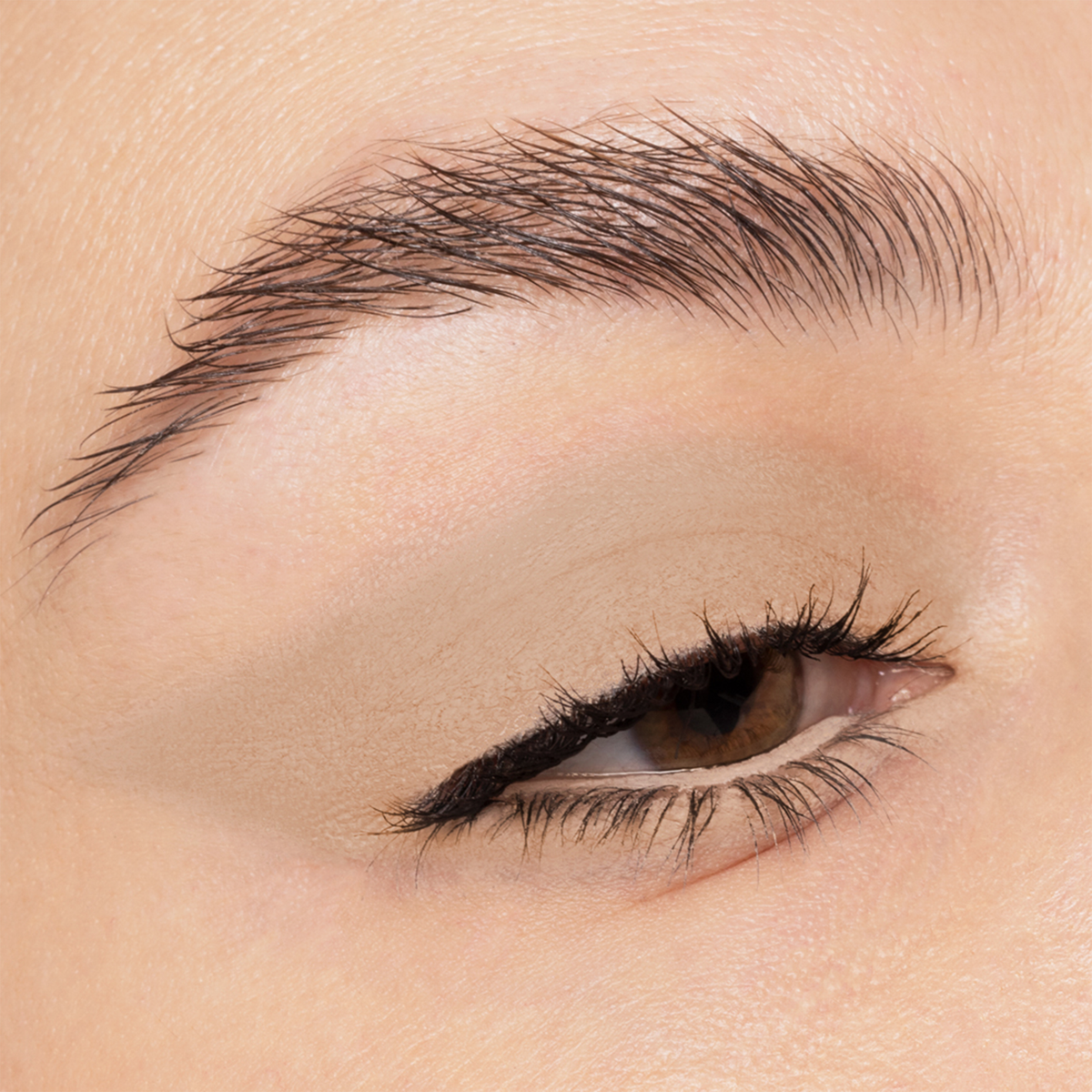 Nahaufnahme eines braunen Auges mit geflügeltem schwarzem Liner und gepflegten Augenbrauen, kreiert mit NABLA Cosmetics Cupids Arrow Longwear Stylo.