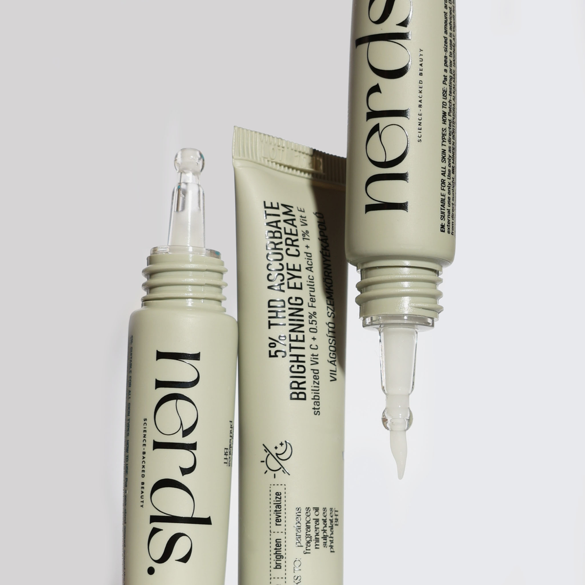Drei Tuben der NERDS. 5% THD Ascorbate Brightening Eye Cream, mit zwei Tuben mit Applikatoren und sichtbarer Creme.