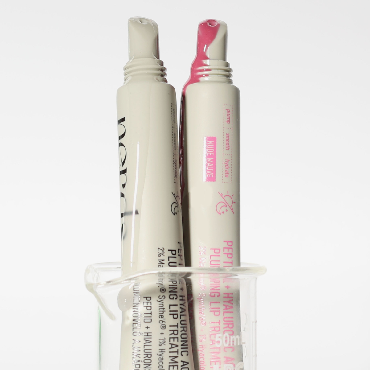 Zwei Tuben der NERDS. Peptide + Hyaluronic Acid Lip Treatment stehen in einem klaren Glasbecher.