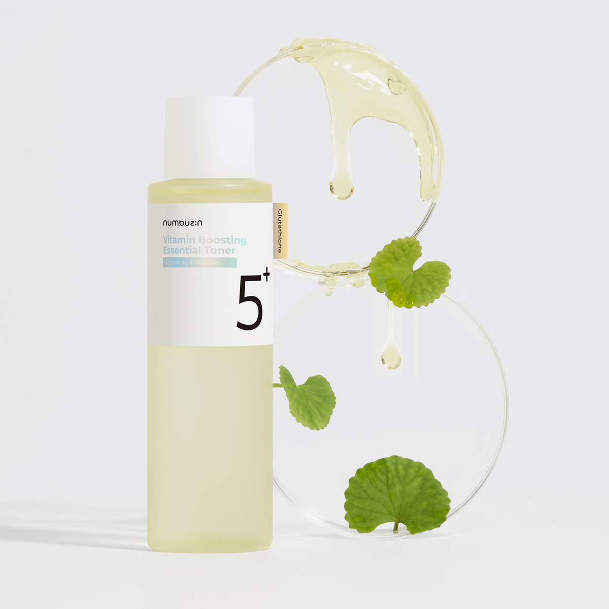 Der Numbuzin No. 5+ Vitamin Boosting Essence Toner 200 ml besticht durch ein frisches Design mit grünen Blättern und Flüssigkeitstropfen im Hintergrund.