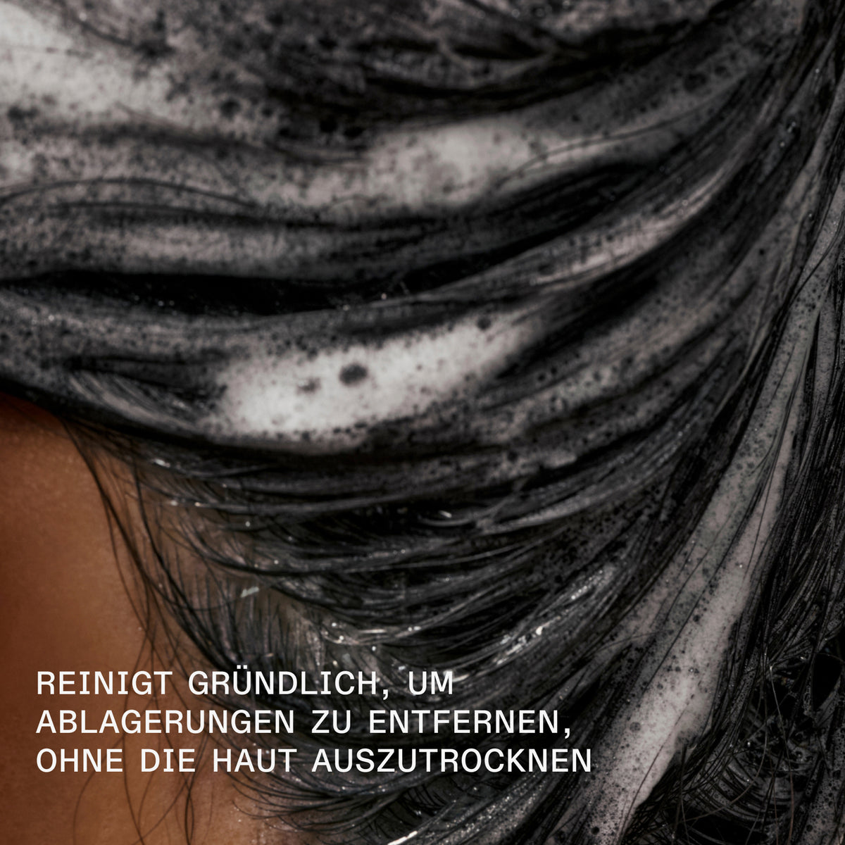 Nahaufnahme schwarzer Haare voller Schaum des N°4C Bond Maintenance Clarifying Shampoo; daneben Text: " reinigt gründlich, um ablagerungen zu entfernen, ohne die Haut auszutrocknen."