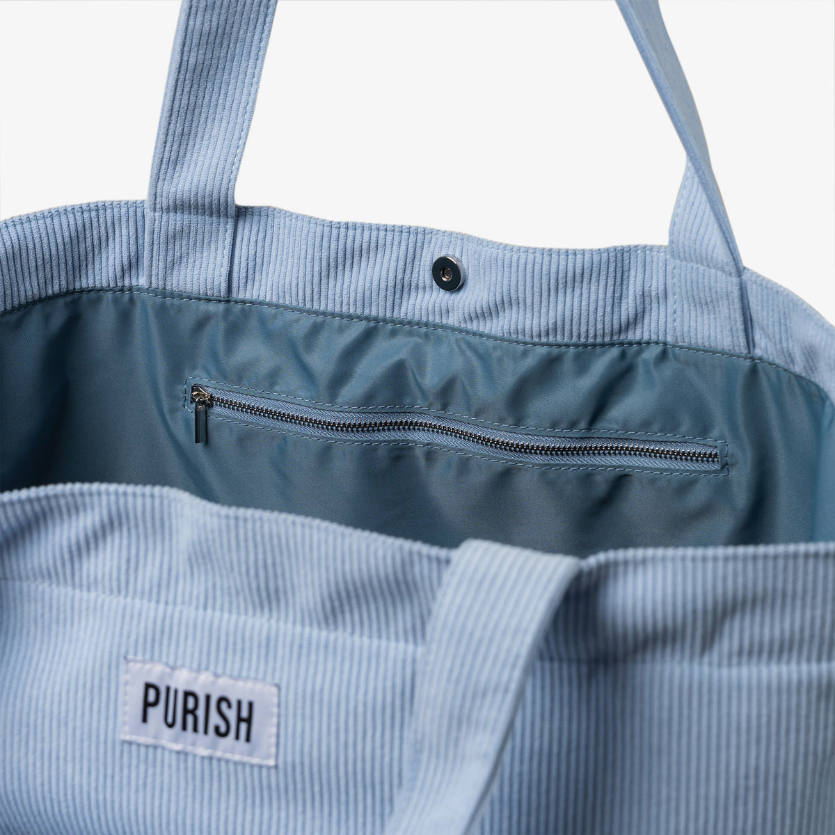 Die PURISH Beach Bag zeigt einen offenen Blick auf die Innentasche mit Reißverschluss und einen sicheren Druckknopfverschluss.