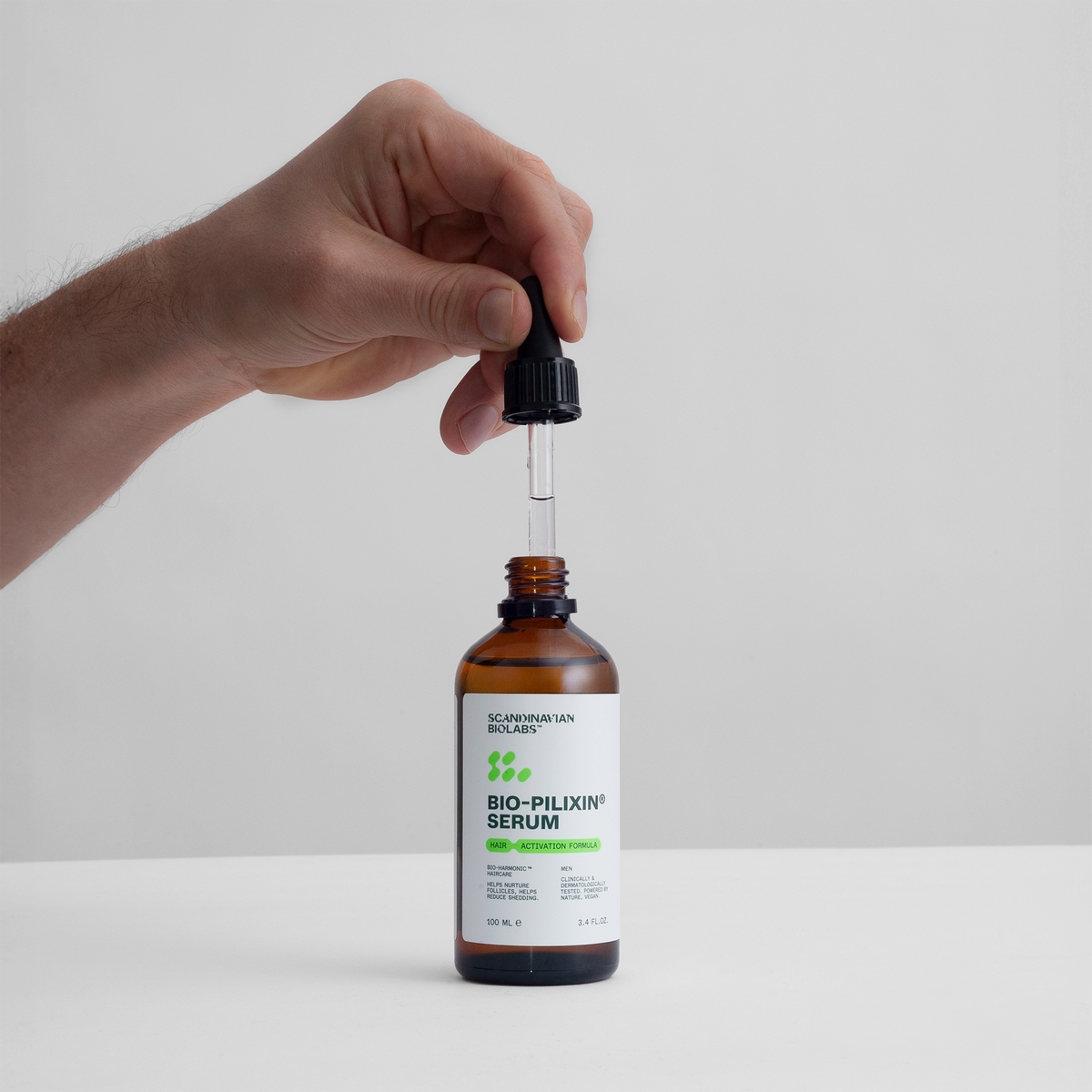 Eine Hand hält einen Tropfer über einer braunen Flasche mit der Aufschrift "Bio Plixin Serum" von Scandinavian Biolabs vor einem weißen Hintergrund.